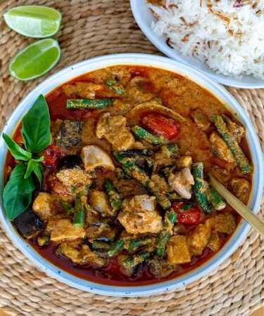 A bowl of Chicken Thai Red Curry served with steamed rice, garnished with fresh herbs — photographed at DeFlambe, a top-rated restaurant in Blue Area, Elysium Tower, Islamabad, near Centaurus.